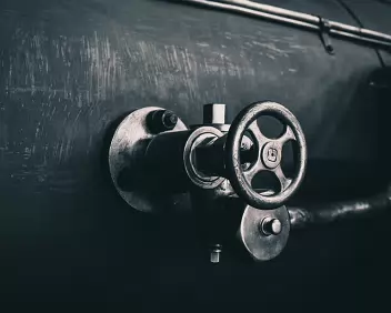 Iron Throttle Metal valve wheel mounted on the side of a steam-locomotive boiler.