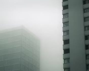 Distant Towers Two buildings emerge from fog, their outlines partially dissolved. Reduced contrast and softened edges shift attention from detail to mass, emphasizing...