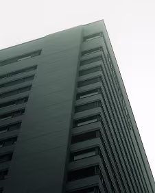 Vertical Quiet Viewed from below, the façade rises into muted sky and haze. The upward perspective compresses the frame, transforming architecture into a study of tone,...